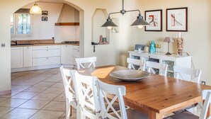 Une cuisine moderne avec des meubles blancs, une table à manger en bois et un bar pour prendre le petit-déjeuner.