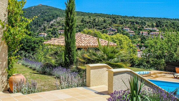 Une villa dotée d’un toit en tuiles, entourée d’une végétation luxuriante et agrémentée d’une piscine.