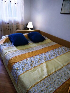 A bedroom with a bed, pillows, a lamp, and a window with curtains.