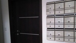 Una puerta con un buzón y buzones adosados a la pared, numerados del 1 al 9.