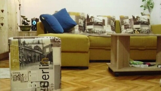 Un salón con un conjunto de sofá, una mesa de centro y un adorno con una imagen de un paisaje urbano.