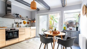 Une cuisine moderne dotée d’un four encastré, de meubles en bois et d’un coin repas avec une table ronde et des chaises.