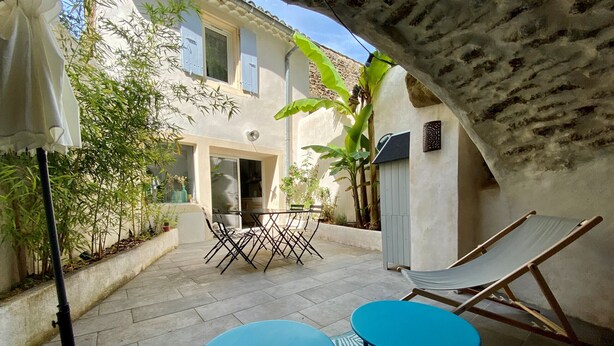 Un espace patio aménagé avec une table et des chaises, un hamac et des plantes en pot.