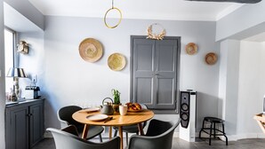 Une cuisine moderne avec une table ronde en bois, des chaises noires et une porte grise.