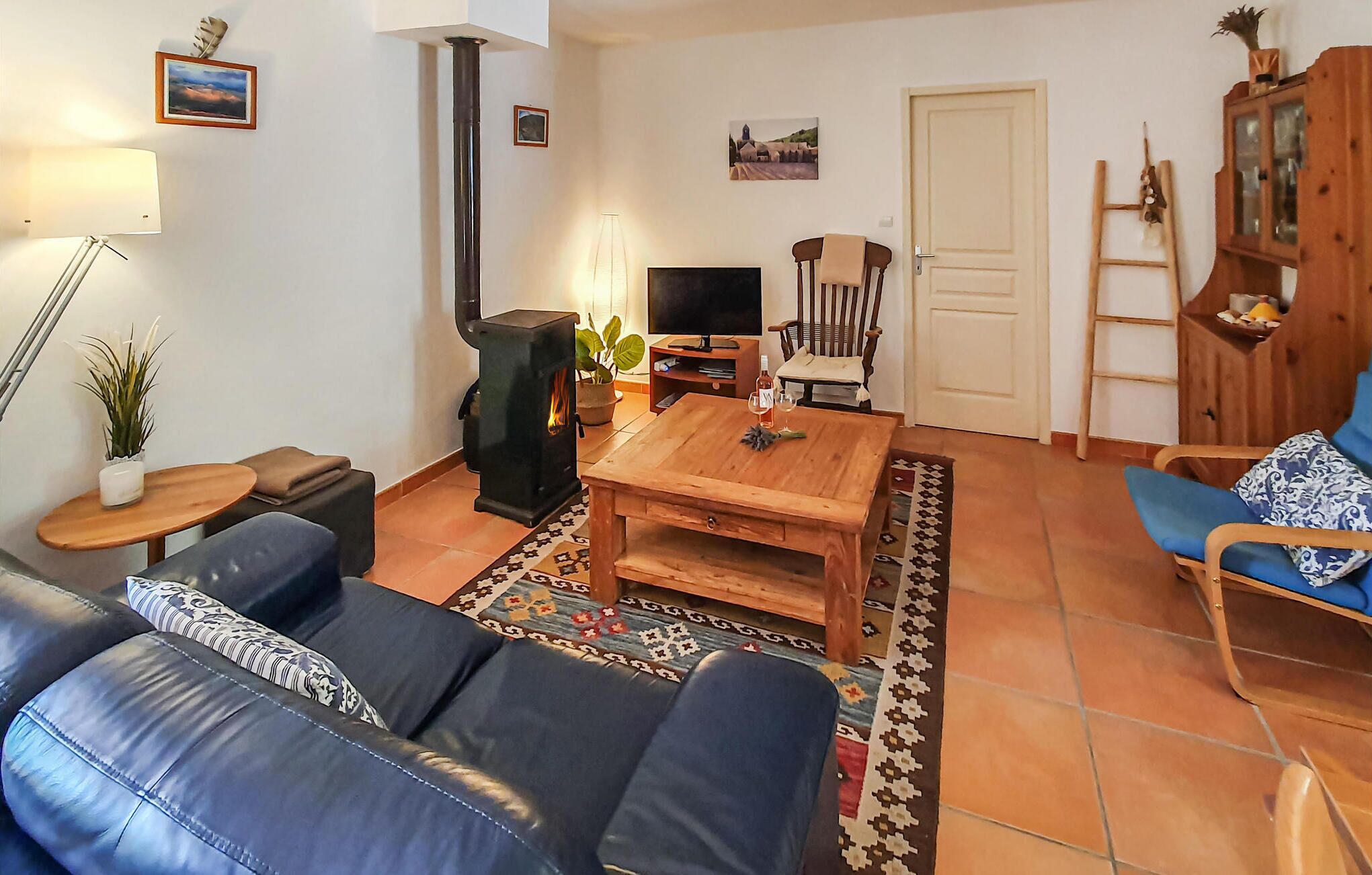 Een woonkamer met een bank, een salontafel, een televisie, een open haard en een deur.
