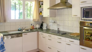 Une cuisine avec des armoires blanches, une hotte de cuisinière en acier inoxydable, un four à micro-ondes et un four encastré.