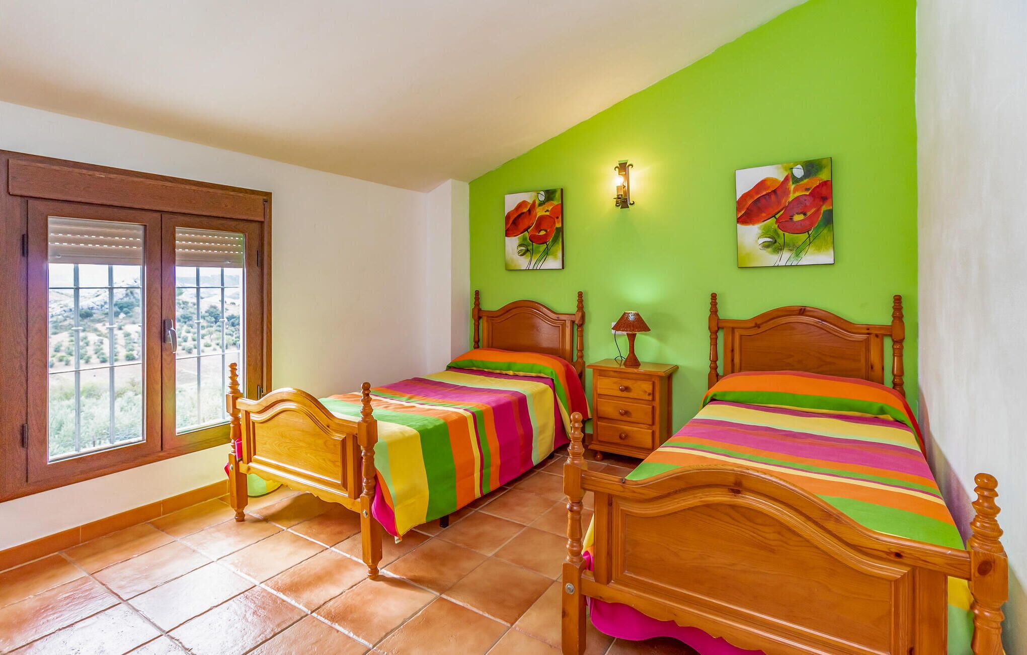Un dormitorio con dos camas de madera, una mesita de noche y una ventana con persianas.