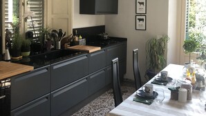 A modern kitchen with a central island, black cabinetry, and a dining area with a table set for two. - Apartment a stone's throw from the walls (Lucca)
