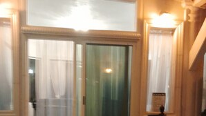 A building entrance with a glass door, a small outdoor area with a plant, and a sign on the wall.