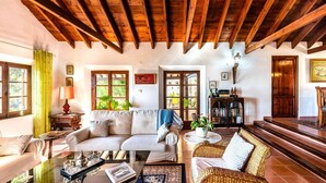 A cozy living room with a wooden ceiling, a sofa, a coffee table, and a bookshelf. - Villa La Saliega Almuñécar by Ruralidays (Granada)