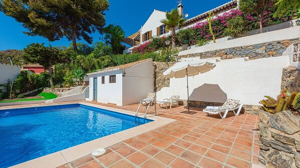 A swimming pool with lounge chairs and a stone wall.