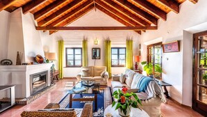 A spacious living room with a fireplace, a sofa, a coffee table, and a dining area with a bench. - Villa La Saliega Almuñécar by Ruralidays (Granada)