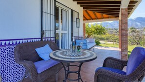 An outdoor patio with wicker furniture, a tiled table, and a view of mountains.