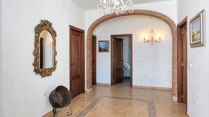 A hallway with a large mirror, a chandelier, and a patterned rug.