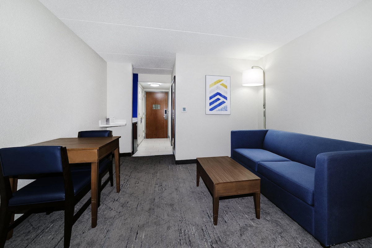 Una habitación con una mesa de madera, un sofá azul y una lámpara.