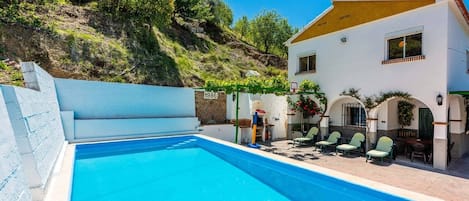 Una piscina con un edificio blanco y una colina al fondo.