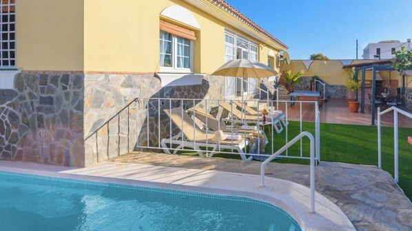 A swimming pool area with lounge chairs and a stone wall. - Casa Layda Torrox by Ruralidays (Málaga)
