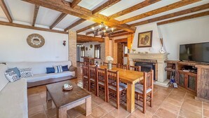 Ein geräumiges Wohnzimmer mit einem Holzespeisetisch und Stühlen, einer Couch, einem Kamin und einem Fernseher.