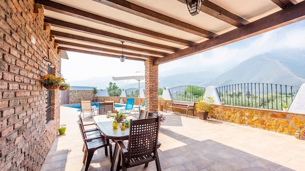 An outdoor patio with a table and chairs, a brick wall, and a view of mountains.