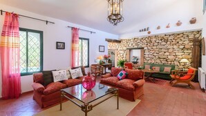 A cozy living room with a stone wall, a glass coffee table, and a fireplace. - Casa Piedras de Gaucín by Ruralidays (Málaga)