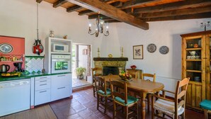 A kitchen with a built-in oven, a dining table with chairs, and a wooden cabinet. - Casa Piedras de Gaucín by Ruralidays (Málaga)