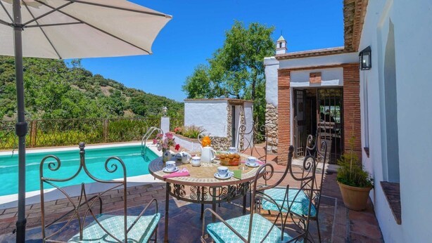 A patio with a pool, outdoor seating, and a view of the surrounding landscape. - Casa Piedras de Gaucín by Ruralidays (Málaga)
