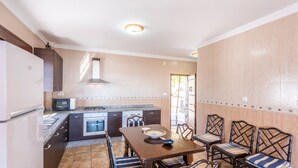 A compact kitchen with a dining area, featuring a central island, built-in appliances, and a view to the outside. - Villa Eugenia Torrox by Ruralidays (Málaga)