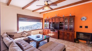 A living room with a sectional sofa, a coffee table, wooden cabinets, a television, and a fireplace. - Villa Eugenia Torrox by Ruralidays (Málaga)