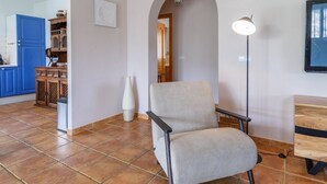A living room with a beige armchair, a floor lamp, and a TV on a wooden stand. - Cortijo Baeza Torrox by Ruralidays (Málaga)