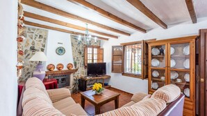 Ein gemütliches Wohnzimmer mit gestreiften Sofas, einem Kamin, einem Fernseher und einem Schrank mit Geschirr.