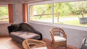 A room with a sofa, two wicker chairs, a window with a view of greenery, and a potted plant. - Nice home in Thueyts with WiFi (Thueyts)