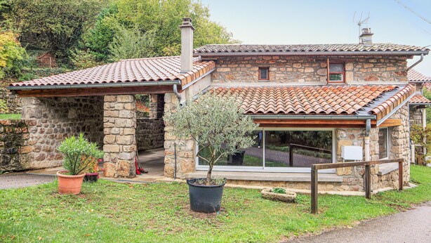 A stone house with a tiled roof, a small porch, and a potted tree in the front yard. - Nice home in Thueyts with WiFi (Thueyts)