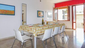 A dining area with a table set for four, white chairs, and a bottle of wine. - 3 bedroom awesome apartment in Bibione (Bibione)