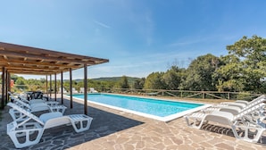Une piscine avec des chaises longues et un espace de détente abrité.
