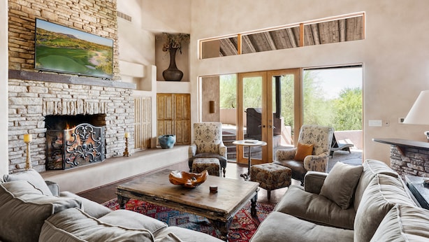 A spacious living room with a stone fireplace, comfortable seating, and large windows offering a view of the outdoors. - ROCKSTAR HOME in DESERT MOUNTAIN - N SCOTTSDALE-PET FRIENDLY-CaveCreek/Carefree (Scottsdale)