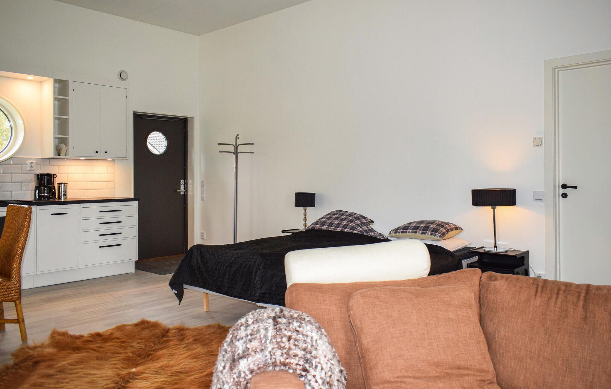A bedroom with a bed, bedside tables, a chair, a fur rug, a wardrobe, a mirror, and a door.
