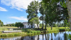 A lakeside building with a dock, surrounded by trees and a calm water body. - Cozy apartment in Lagan with WiFi (Lagan)