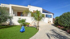 Une maison moderne à deux étages, dotée d’une pelouse bien entretenue et d’une allée menant à l’entrée.
