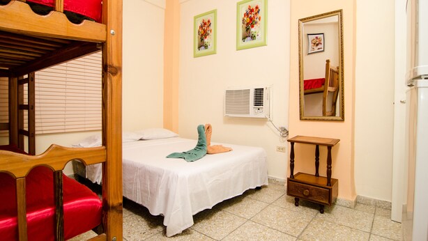 Ein Schlafzimmer mit Etagenbett, einem Einzelbett, einem kleinen Tisch und einem Spiegel.