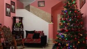 Ein Wohnzimmer mit Weihnachtsbaum, einer Couch, einem Holzstuhl und einer Treppe.
