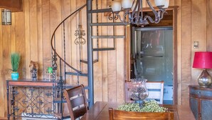 Un intérieur en bois avec un escalier en colimaçon, une table à manger avec des chaises et un lustre.