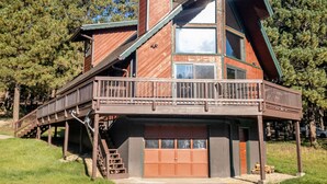 Une cabane en bois à deux étages, dotée d’un balcon, d’un garage et d’une cheminée.