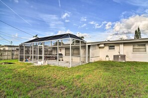 Een huis met een ruime glazen patio, een omheinde achtertuin en een heldere lucht.