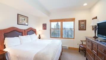 Relax in a serene hotel room with a large bed, framed artwork, and a functional workspace.