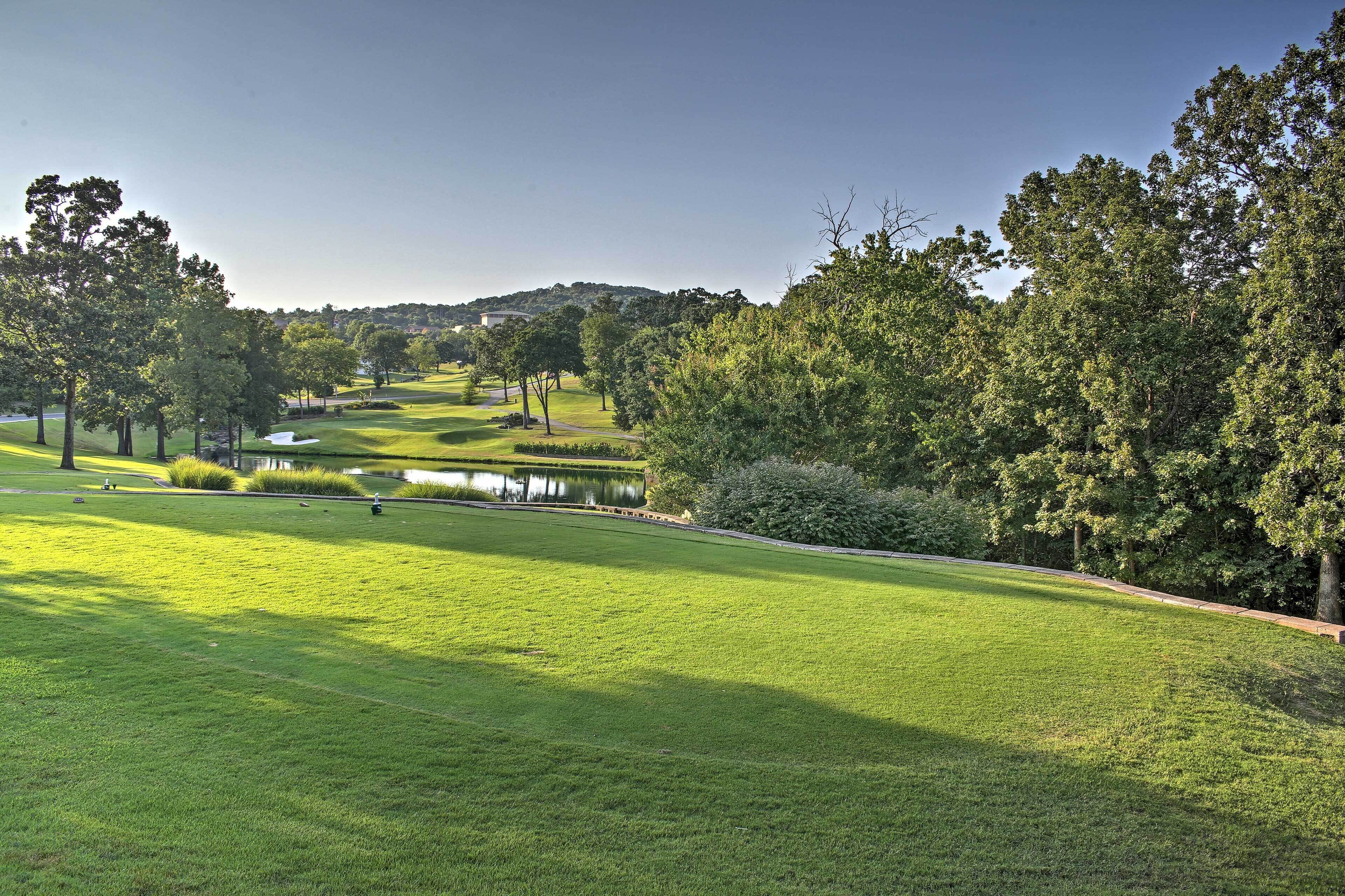 Un parcours de golf avec un étang, des arbres et un ciel dégagé.