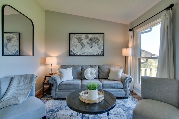 A living room with a grey sofa, two armchairs, a coffee table with a plant, and a world map on the wall. - Indoor Pool! Pointe Royale Resort Condo in Branson (Branson)