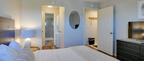 A bedroom with a bed, a dresser, a mirror, and a door leading to a bathroom.