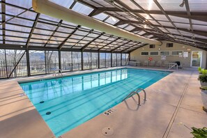 An indoor swimming pool with clear blue water, surrounded by a covered area with a metal roof and glass walls. - Indoor Pool! Pointe Royale Resort Condo in Branson (Branson)
