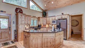 A spacious kitchen with wooden cabinets, a large island, and a view of the outdoors.