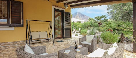 Un patio al aire libre con muebles de mimbre, una mecedora y vistas a las montañas.